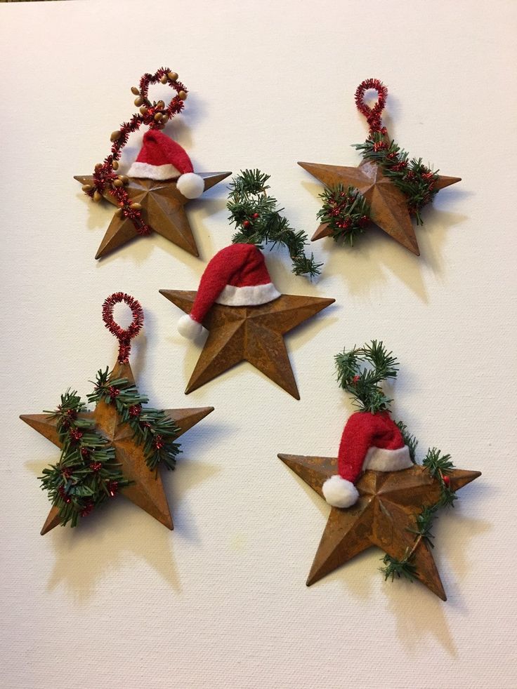 six wooden star ornaments with santa hats and holly wreaths hanging from the top, on a white surface