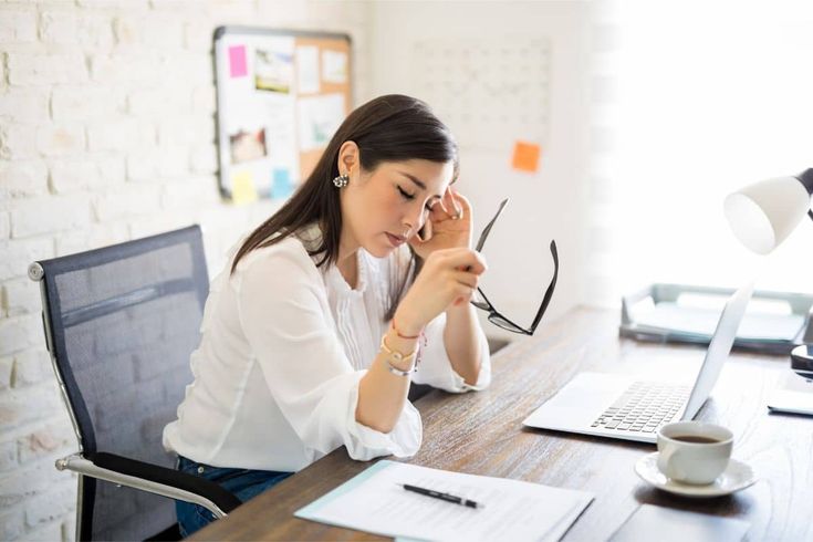 a woman sitting at a desk in front of a laptop