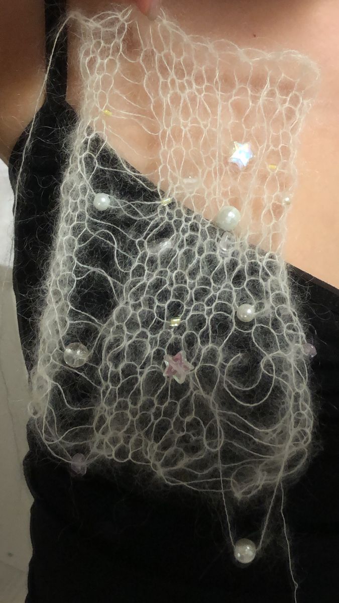 a close up of a woman wearing a black top with white lace on her chest