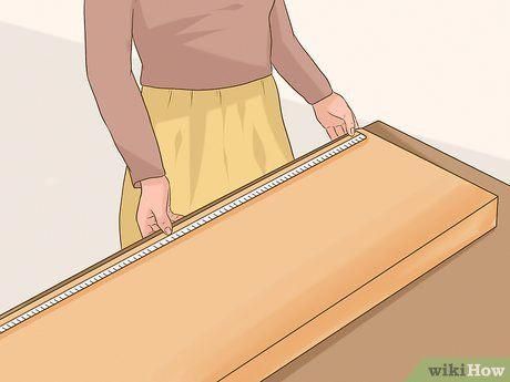 a man measuring the width of a wooden box