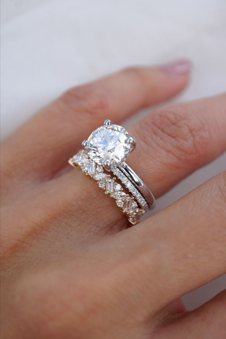 a woman's hand with a wedding ring and engagement band on top of her finger