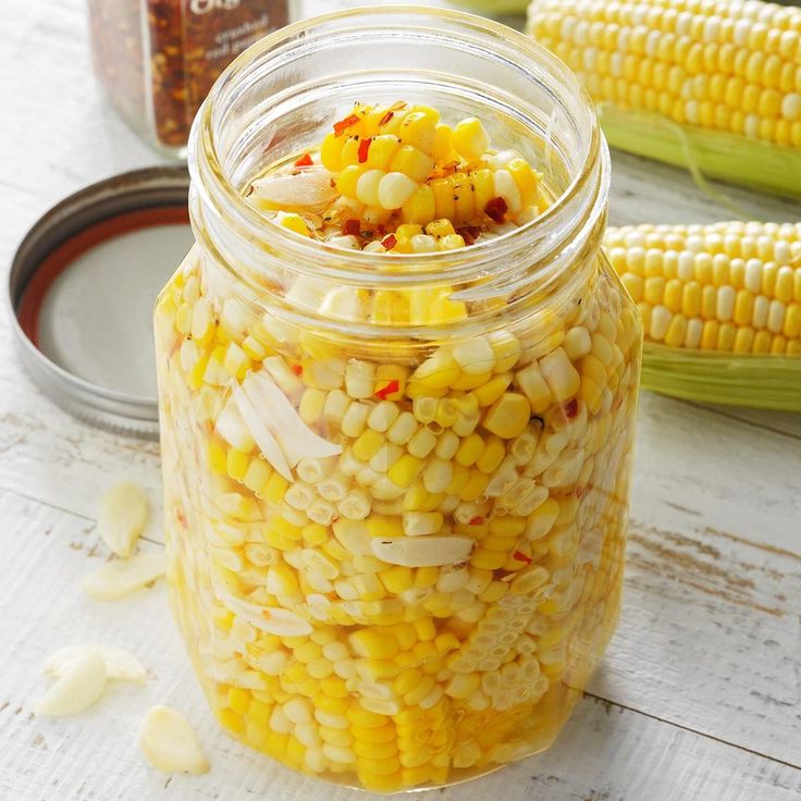 a jar filled with corn sitting on top of a table