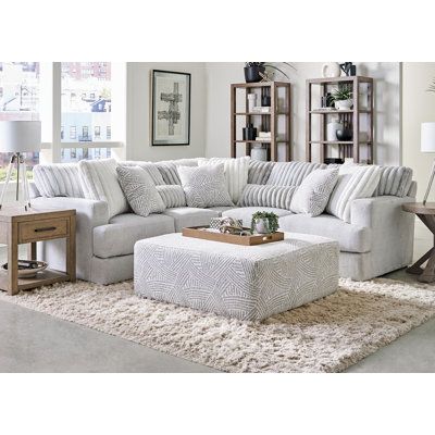 a living room scene with focus on the sectional sofa and footstool in the center