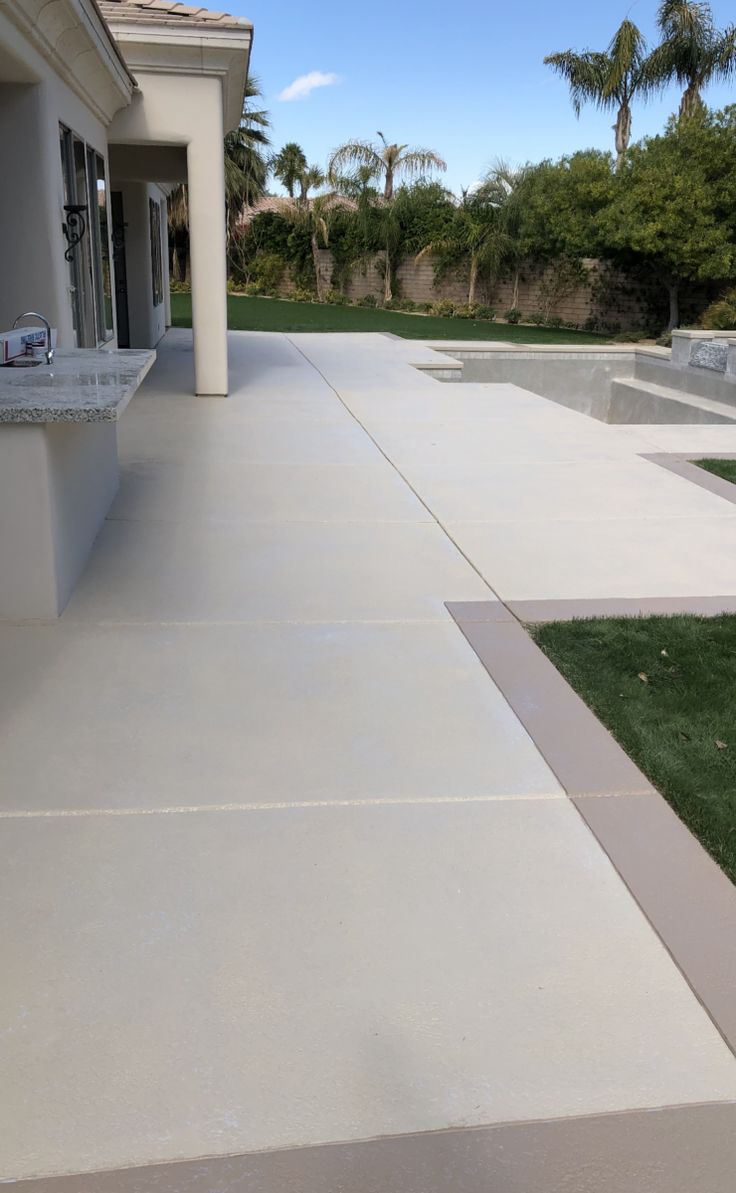 an empty patio with grass and trees in the background