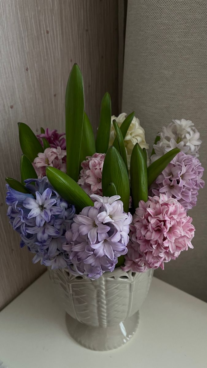 a white vase filled with purple and white flowers