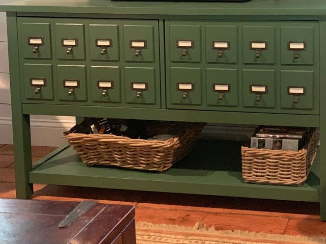 a green cabinet with two baskets underneath it and a television on top of the cabinet