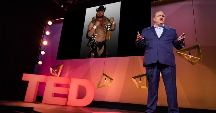 a man in a suit standing on stage with his hands out to the side while speaking