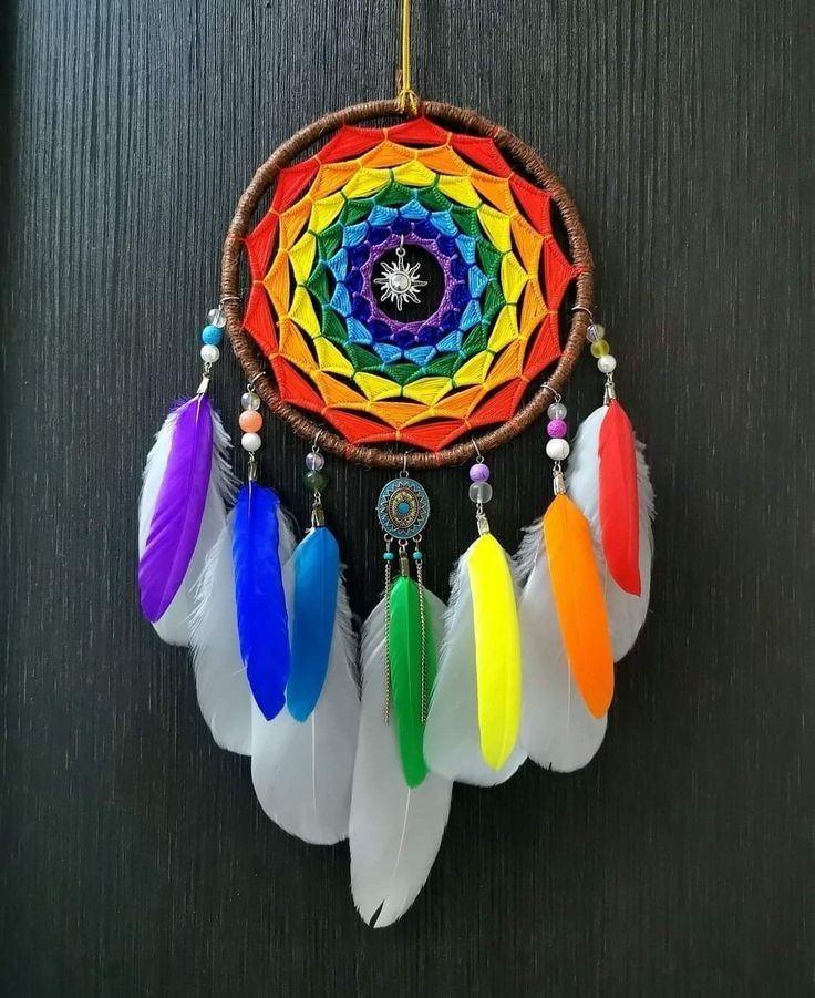 a colorful dream catcher hanging on the wall next to a black door with white feathers