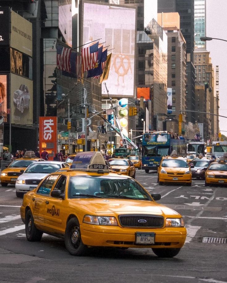 taxi cabs driving down the street in new york city