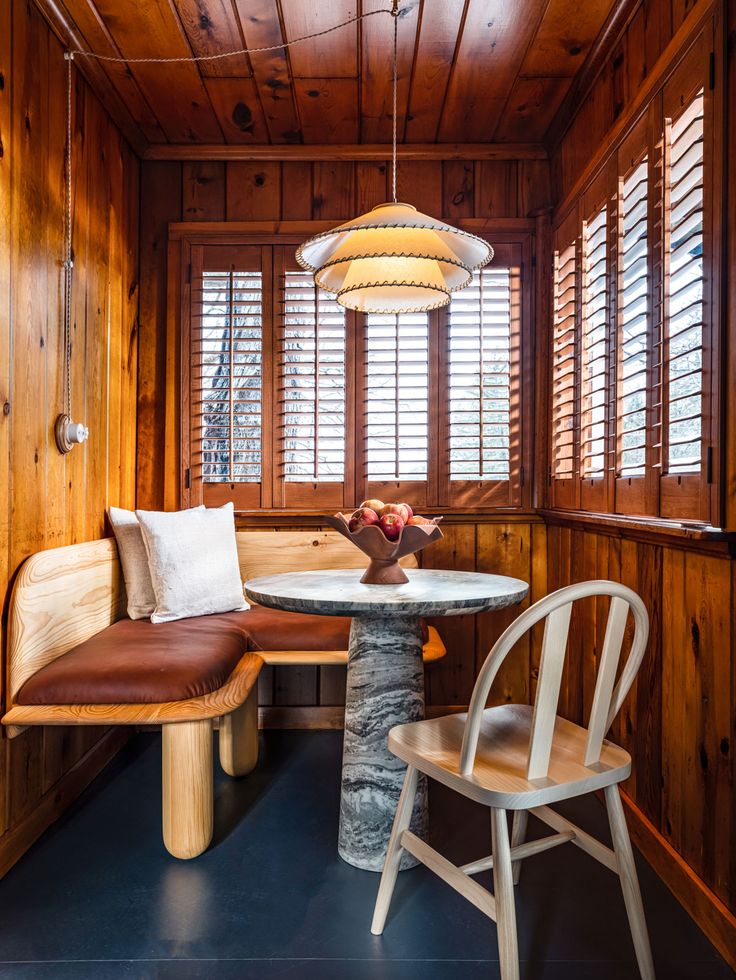 a room with wood paneling and two chairs next to a round table in the corner