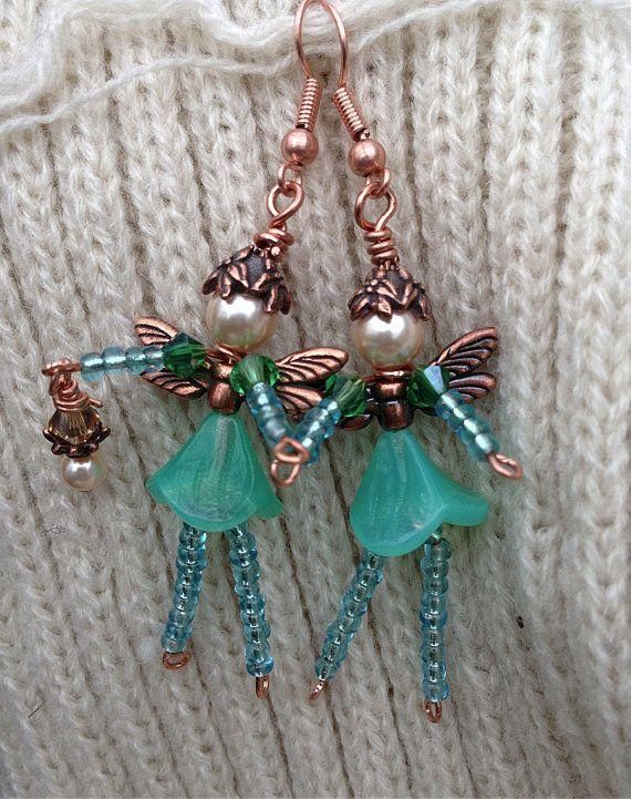 the earrings are made from glass beads and copper wire, with little fairy figures on them