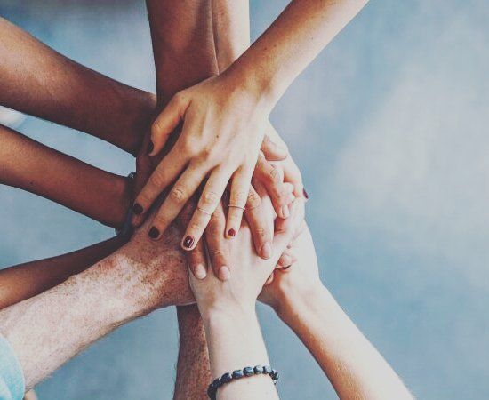 a group of people's hands stacked on top of each other with their fingers together