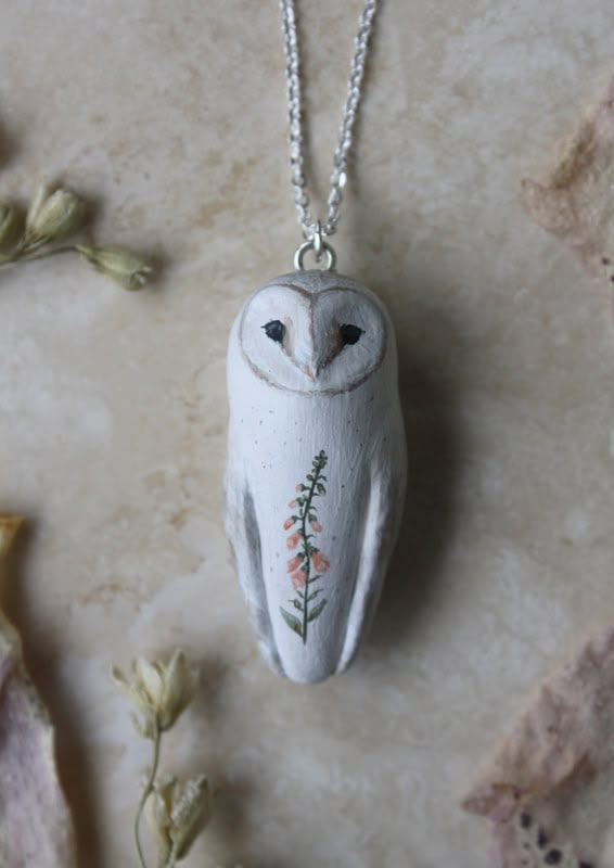 an owl is sitting on the ground next to flowers and a chain that has been placed in front of it