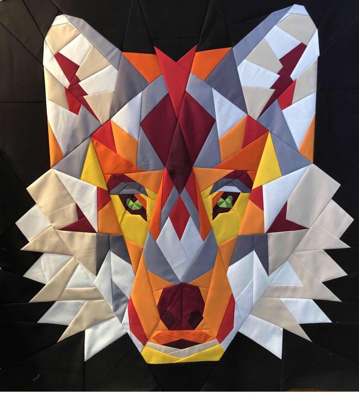 an animal made out of folded paper with green eyes and red, orange, yellow and grey colors