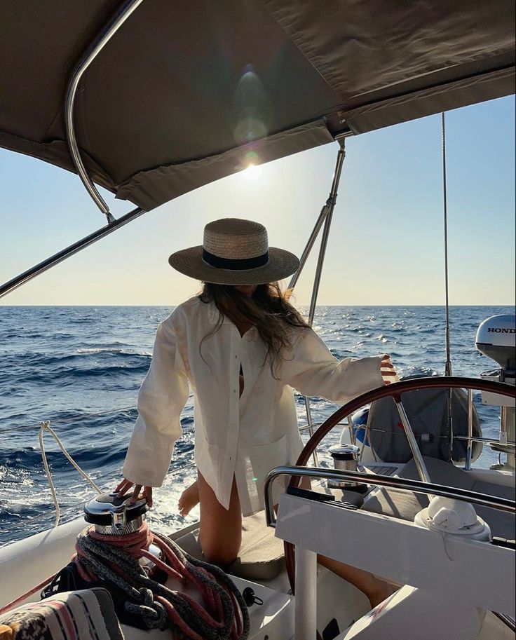 a woman standing on the deck of a sailboat in the middle of the ocean