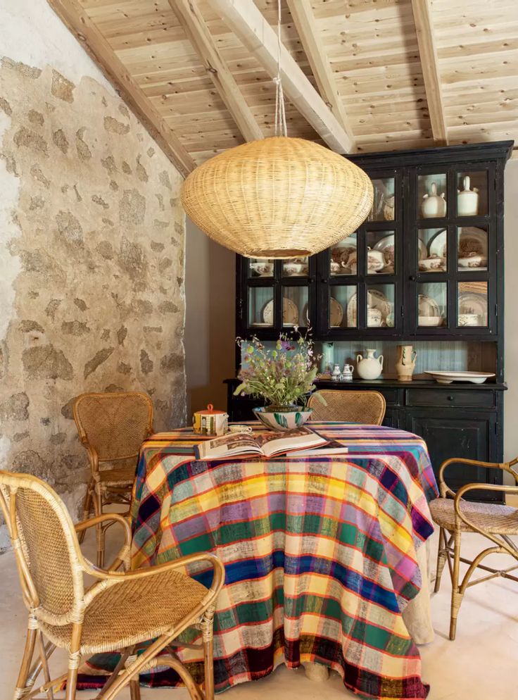 a dining room with chairs and a table covered in a checkered cloth next to a stone wall