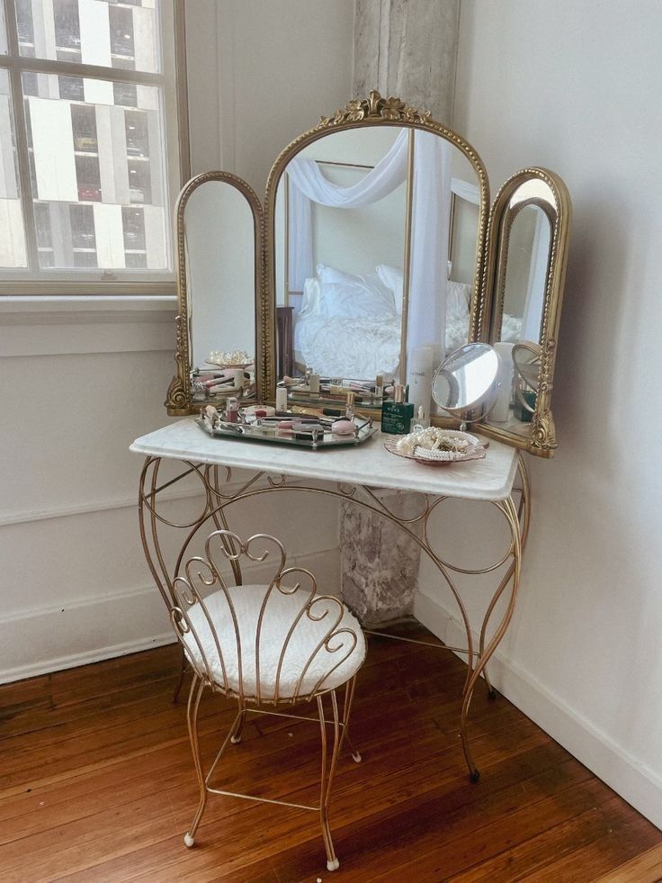 a white vanity with two mirrors on top of it and a chair in front of it