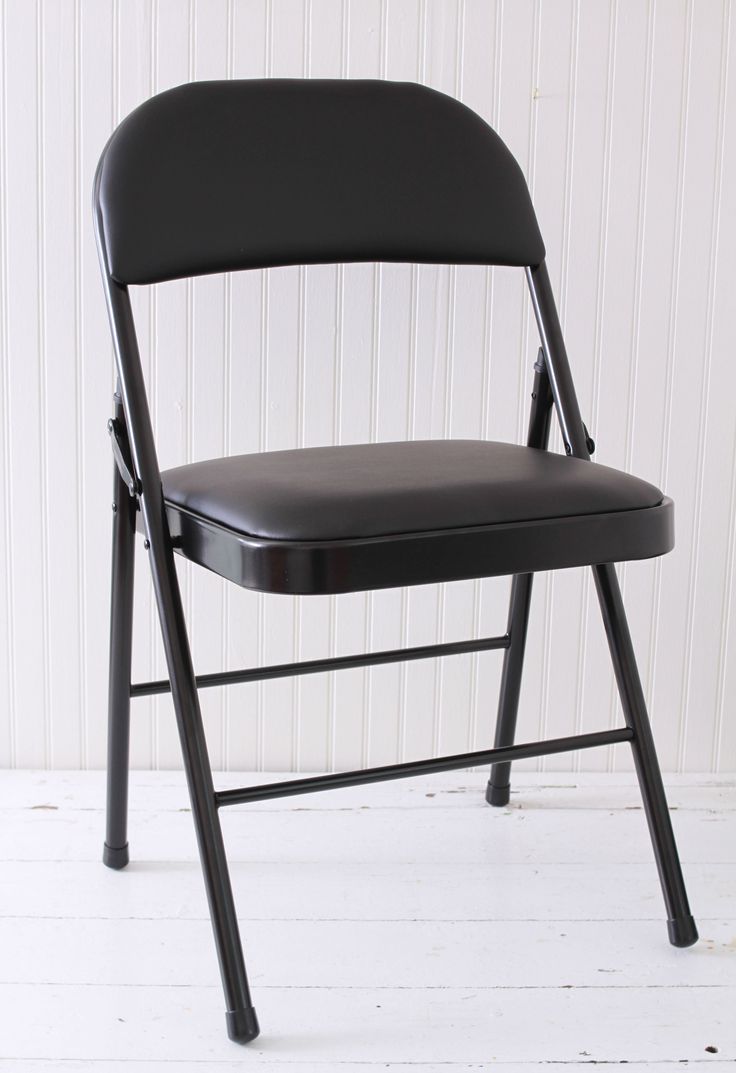 a black folding chair against a white wall