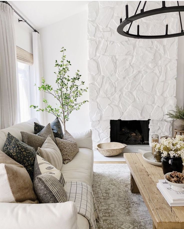 a living room filled with furniture and a fire place in front of a stone wall