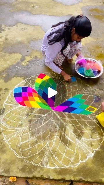 two children are drawing with colored chalks on the ground