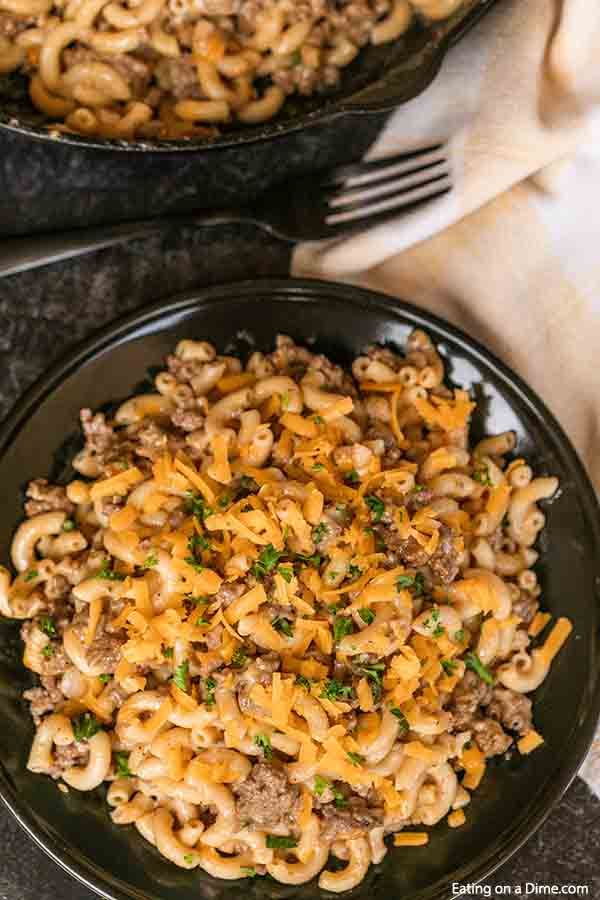 two black plates filled with macaroni and cheese on top of a marble table