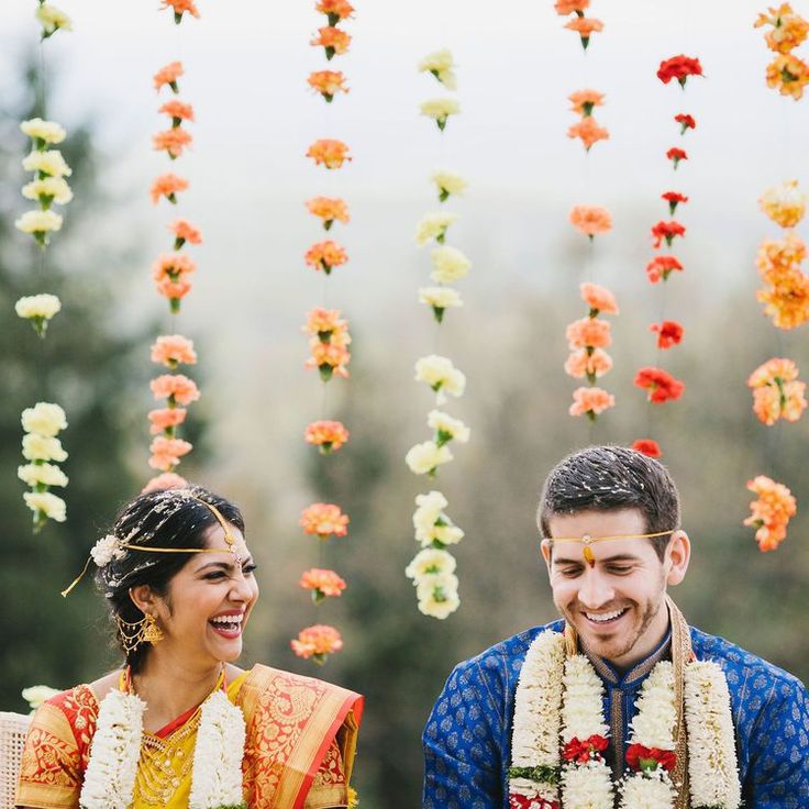 a man and woman standing next to each other in front of flowers