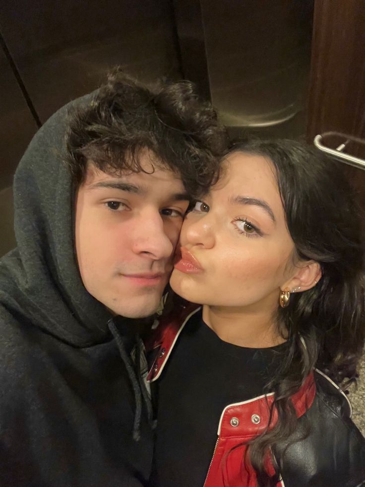 a young man and woman are posing for a selfie in front of a mirror