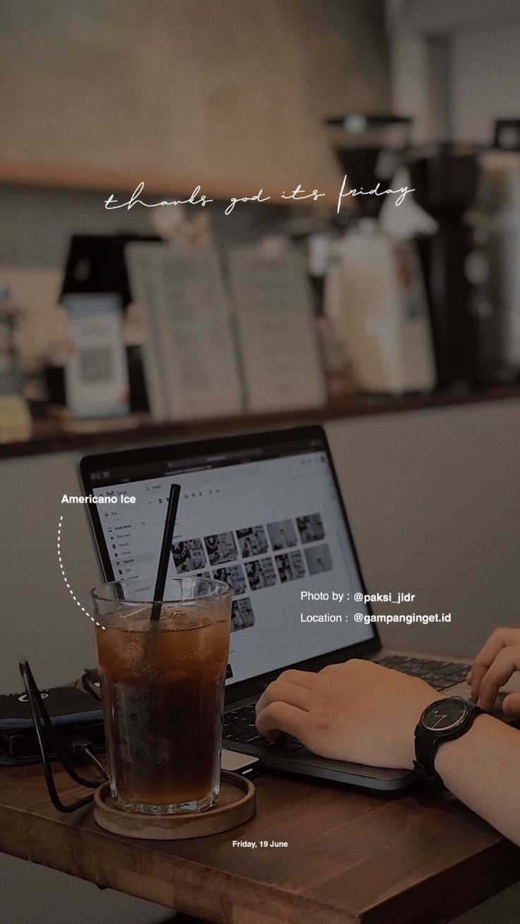 a person sitting at a table with a laptop and drink in front of them on their lap