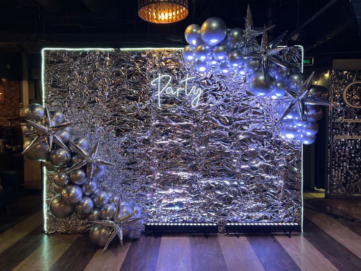 a large piece of art made out of silver foil and balloons on display in a dark room