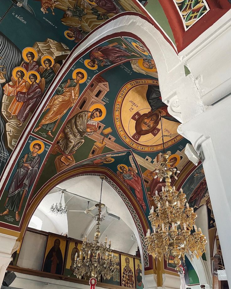 the interior of a church with paintings and chandeliers hanging from it's ceiling