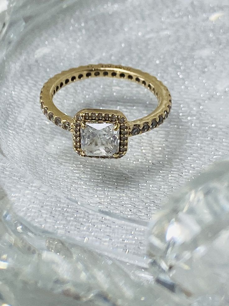 Incorporating a single large Danube -cut cubic zirconia encircled by sparkling clear cubic zirconia accents.This 14 karat yellow gold ring from the PANDORA 2016 WINTER COLLECTION. Condition: Pre-owned .This item doesn't include PANDORA box/pouch. Emerald Cut Cubic Zirconia Halo Diamond Ring, Gold Cubic Zirconia Diamond Ring With Halo, Glamorous Diamond Ring With Brilliant Cut For Gift, Glamorous Brilliant Cut Diamond Ring As Gift, Gold Cubic Zirconia Ring With Halo Detail, Gold Cubic Zirconia Jewelry With Asscher Cut, Gold Diamond Ring With Cubic Zirconia Center Stone, Gold Diamond Ring With Vs Clarity And White Topaz, Gold Crystal Ring With Halo Design For Formal Events