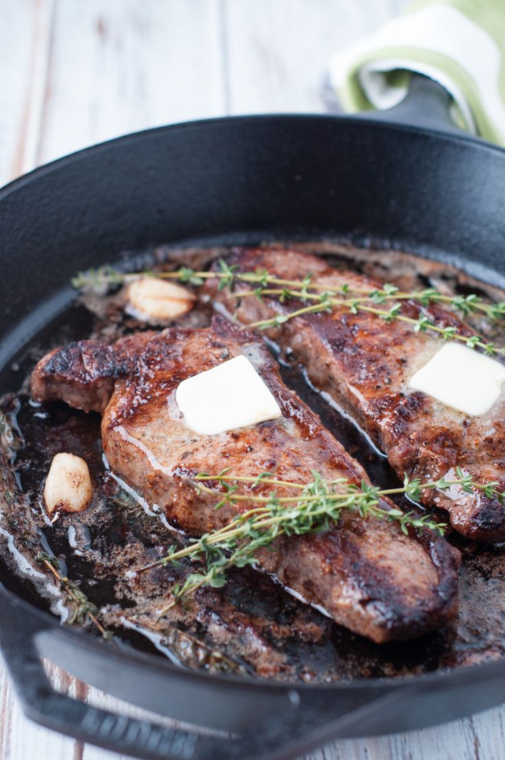 steaks with butter and herbs cooking in a skillet