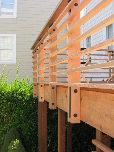 a wooden deck with railings and bushes in the background