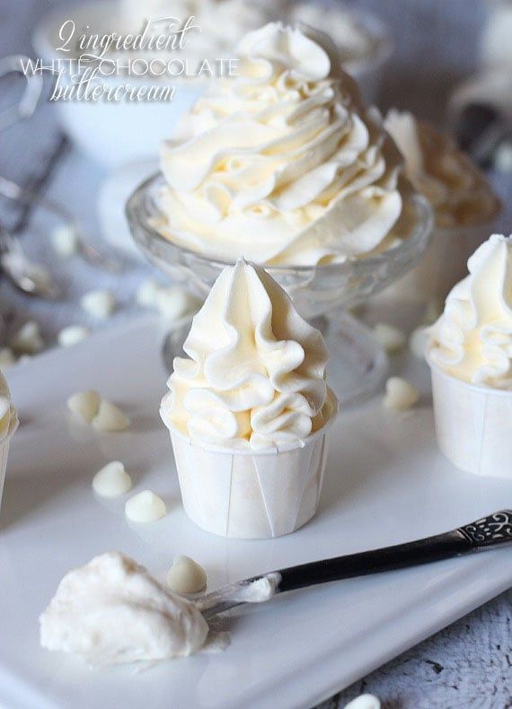 several cupcakes with white frosting on a tray next to other dessert items