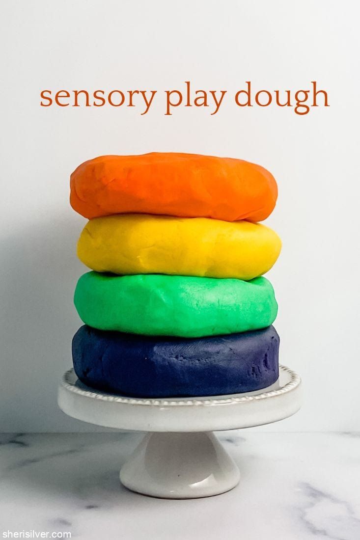 a stack of colorful doughnuts sitting on top of a white cake platter