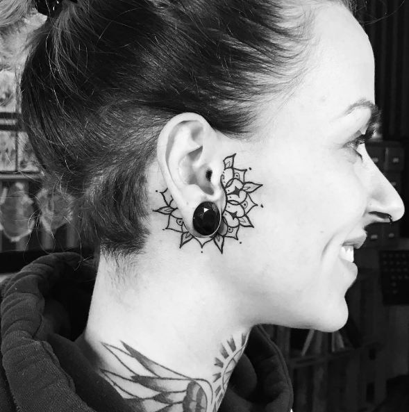 a woman with tattoos on her neck and ear