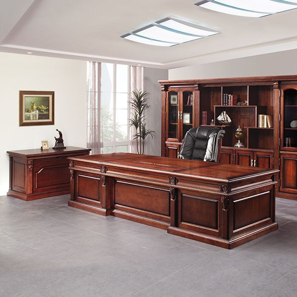 a large wooden desk sitting in front of a bookcase and chair next to a potted plant