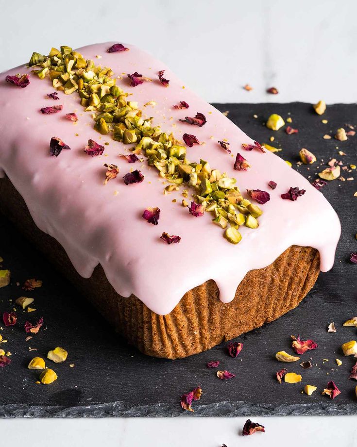 a piece of cake with pink icing and flowers on it sitting on a black plate