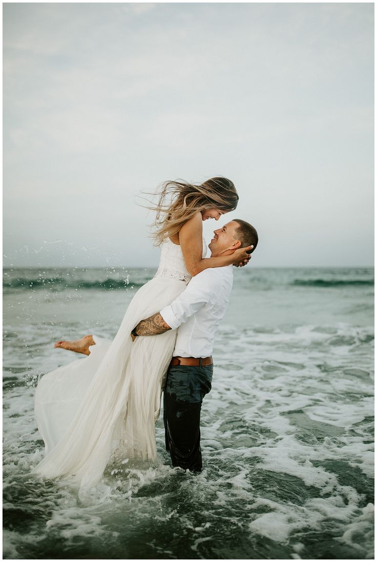 a man and woman in the ocean hugging