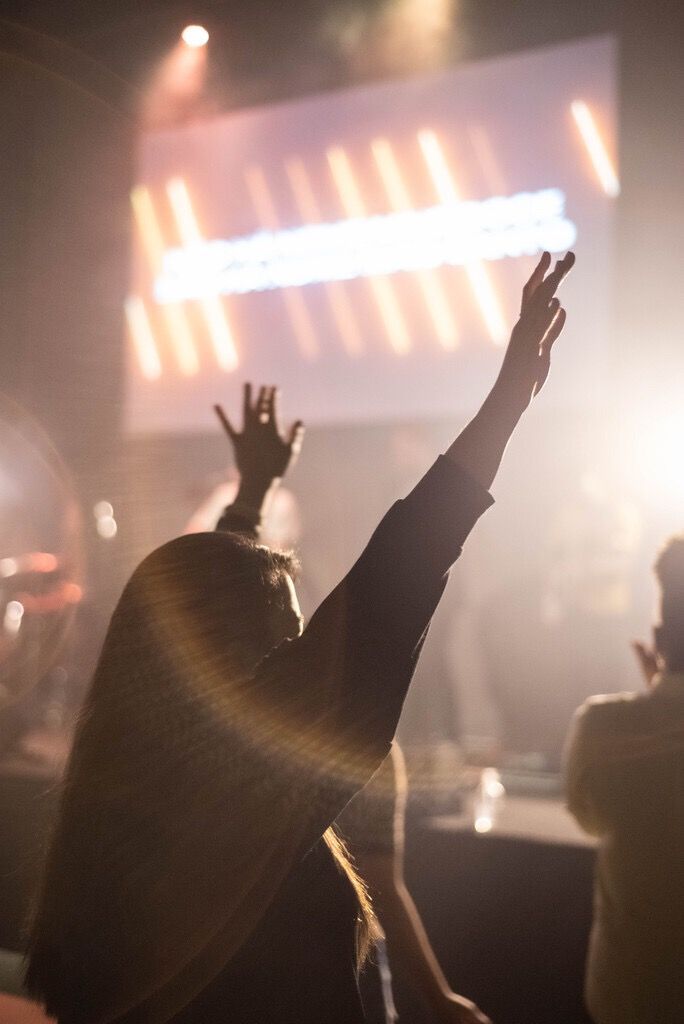 a person raising their hands in the air at a concert