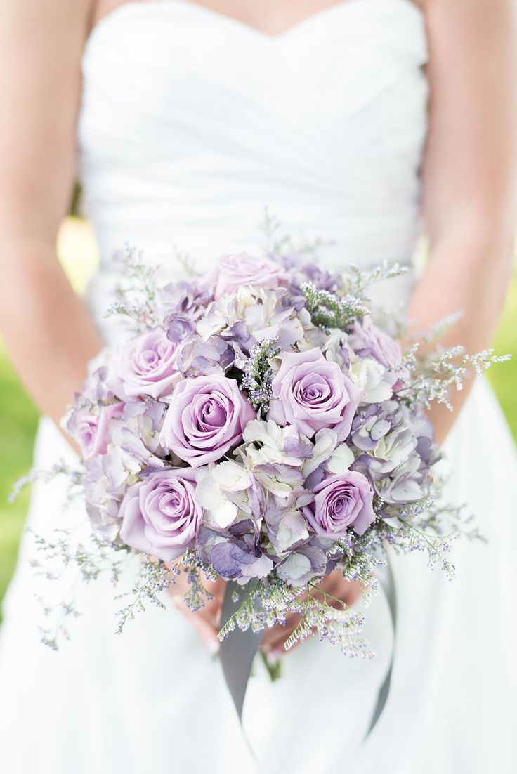 a bride holding a bouquet of purple roses