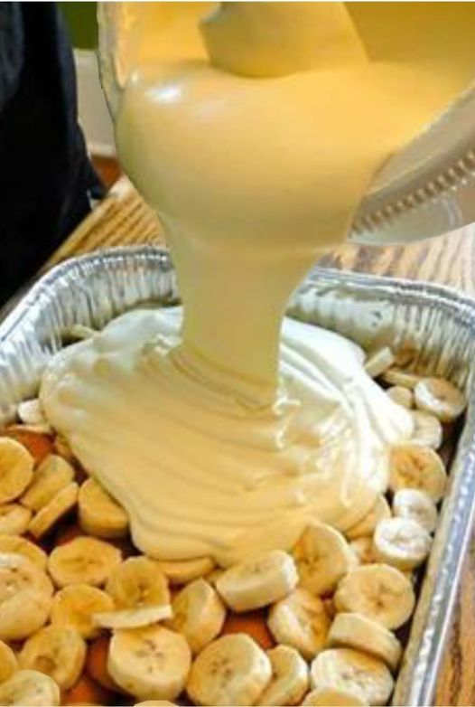 a pan filled with bananas and cream being poured into it