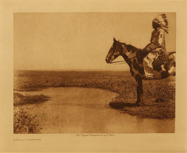 an old photo of a native american man on a horse by the water's edge