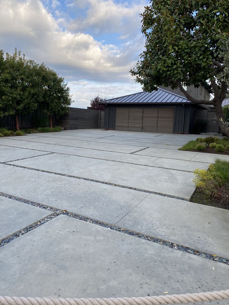 an empty concrete driveway surrounded by trees and bushes