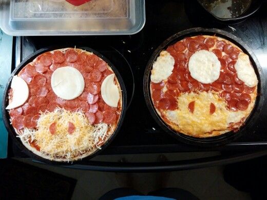 two pizzas sitting in pans on top of a stove