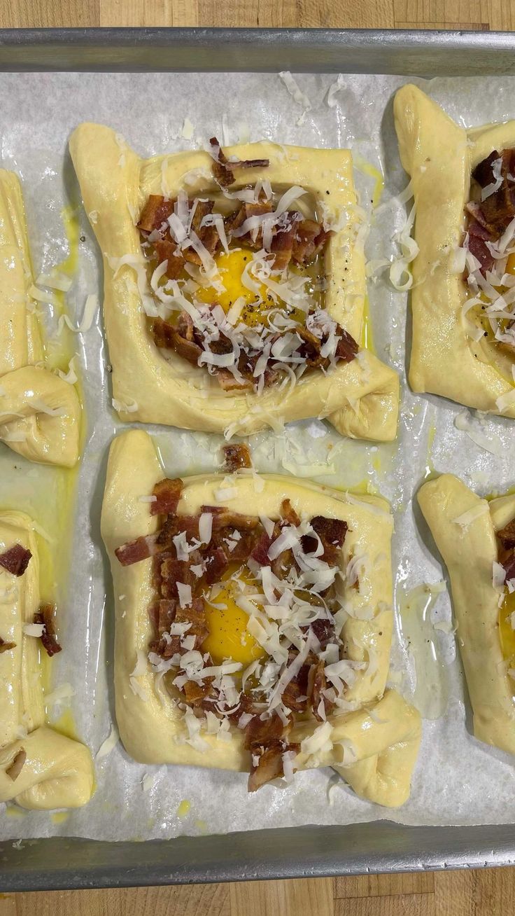 four uncooked pizzas with cheese and bacon on them in a baking pan