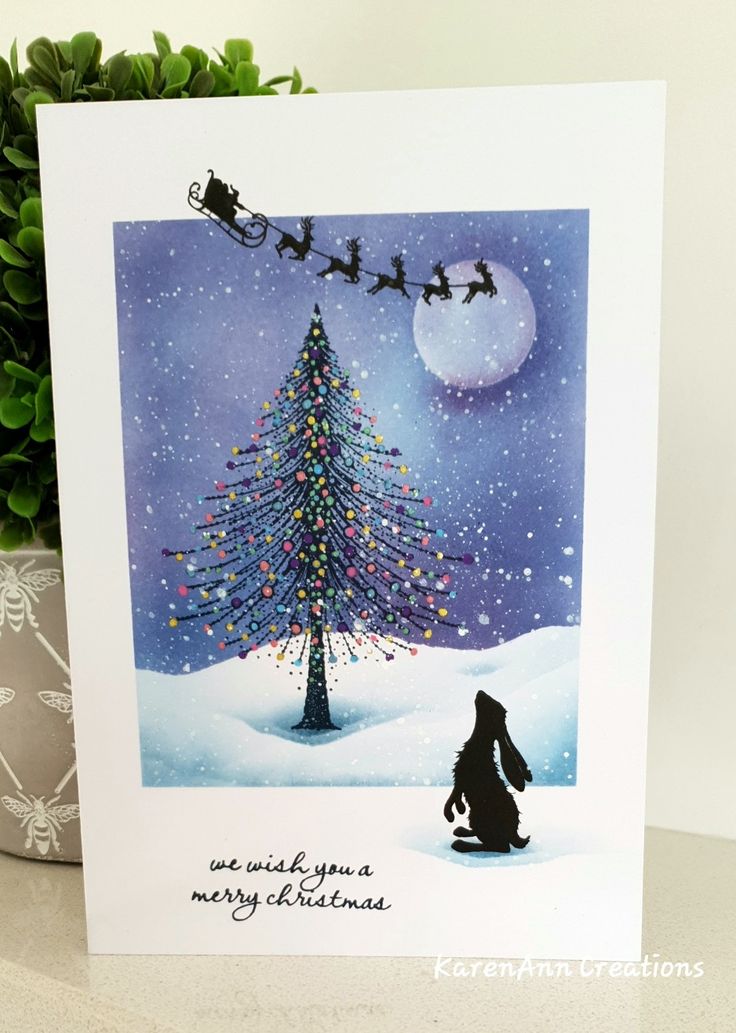 a christmas card with a dog sitting in front of a tree