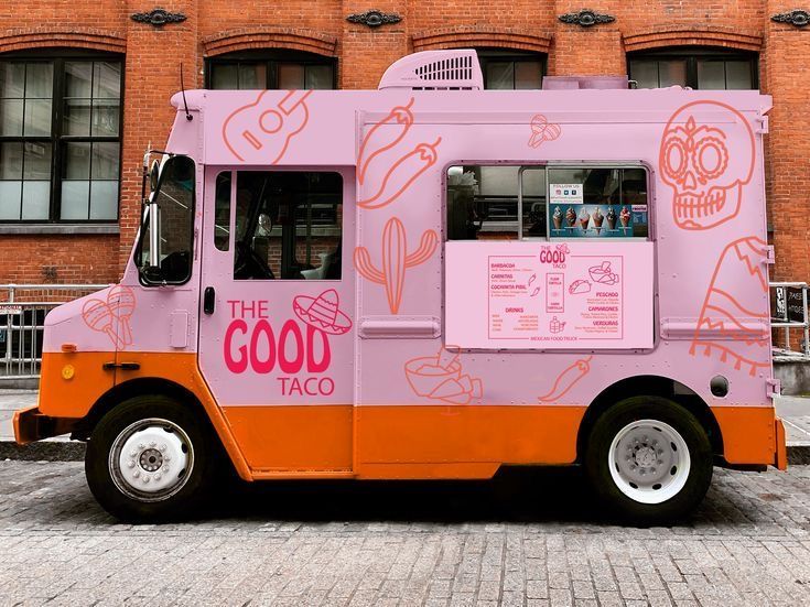 an orange and pink food truck parked in front of a brick building