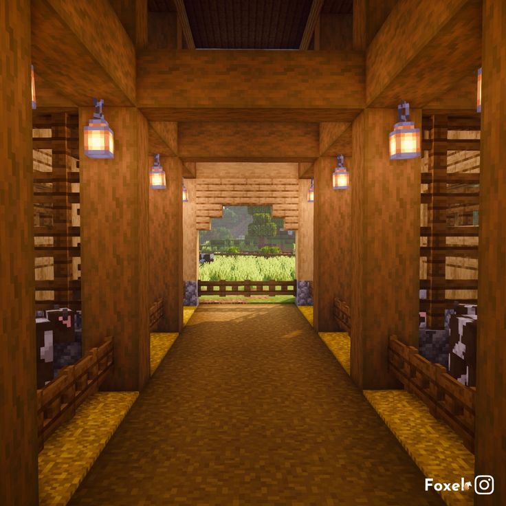 a long hallway with wooden walls and lights on the ceiling, leading to a grassy area