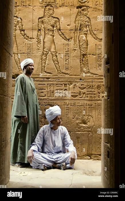 two men sitting in front of an egyptian wall